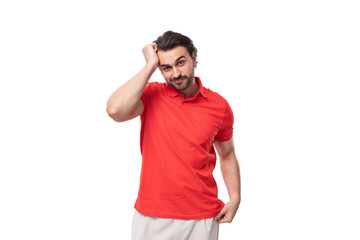 Fototapeta premium a young smart 35 year old european man with a styled haircut and a beard dressed in a red t-shirt stands thoughtfully and reflects on his own development