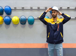 Young man working in a factory,  wearing construction hardhat on his head for safety. Concept of...