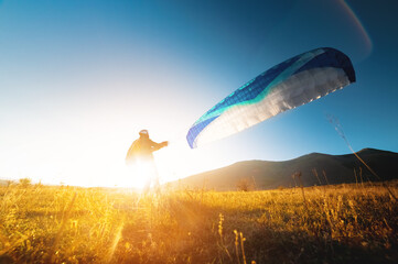 Launching a speedwing from a mountain. A paraglider is preparing to take off from a mountain,...