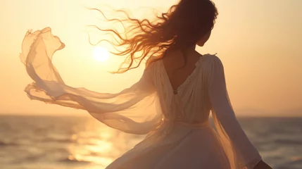 Gardinen Beautiful girl in a white dress dancing on the beach at sunset © tashechka