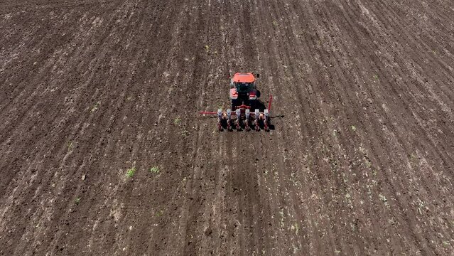 Aerial view tractor cuts furrows in farm field for sowing. An agricultural machine plants the field with agricultural crops, agricultural natural seasonal spring works.Modern agriculture at drone view