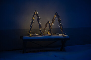 Three home made wooden Christmas trees with lights outside