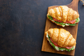 Croissants with salmon, white cheese and arugula. Breakfast.