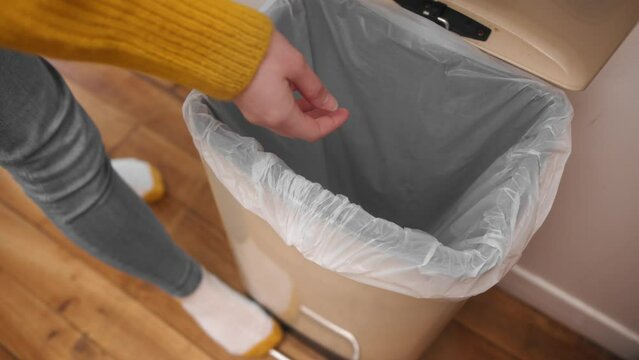 Fit woman throwing trash into bin inside her home, close up view