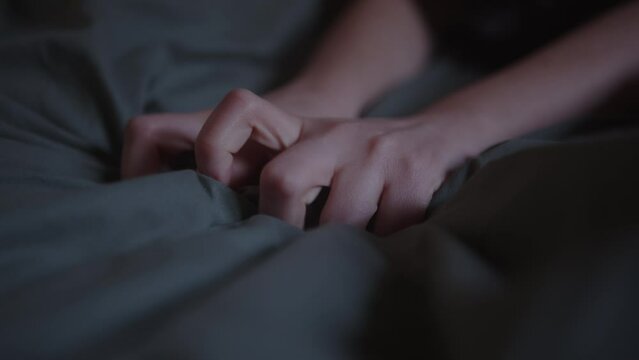 Hands of a woman squeezing the sheets as a sign of pleasure in bed. Orgasm