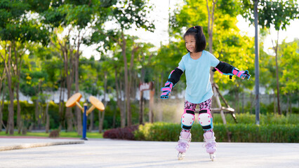 Asian kid girl practicing roller skating. Children wear elbow guard and knee guard to prevent...