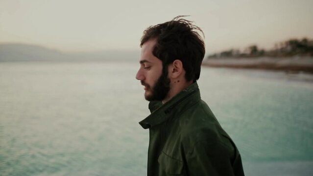 Profile view of grieving bearded man walking on edge of Dead Sea, Israel