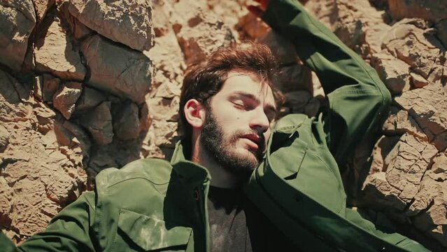 Lifeless body of man with arms spread wide on jagged rocky terrain in desert
