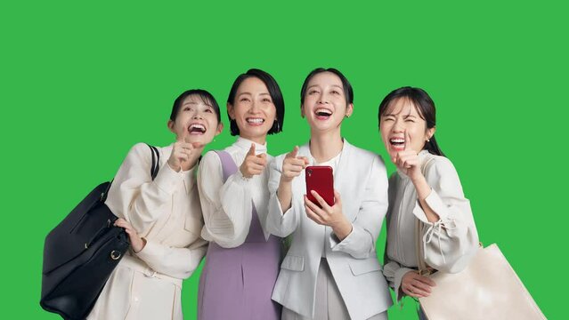 スマホを見ながら観光するミドル女性グループ　クロマキー合成用グリーンバック