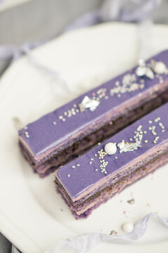 French pastry blueberry opera layered cake with almond violet sponge, buttercream  and chocolate ganache layers, and topped with a glossy chocolate glaze close up selective focus