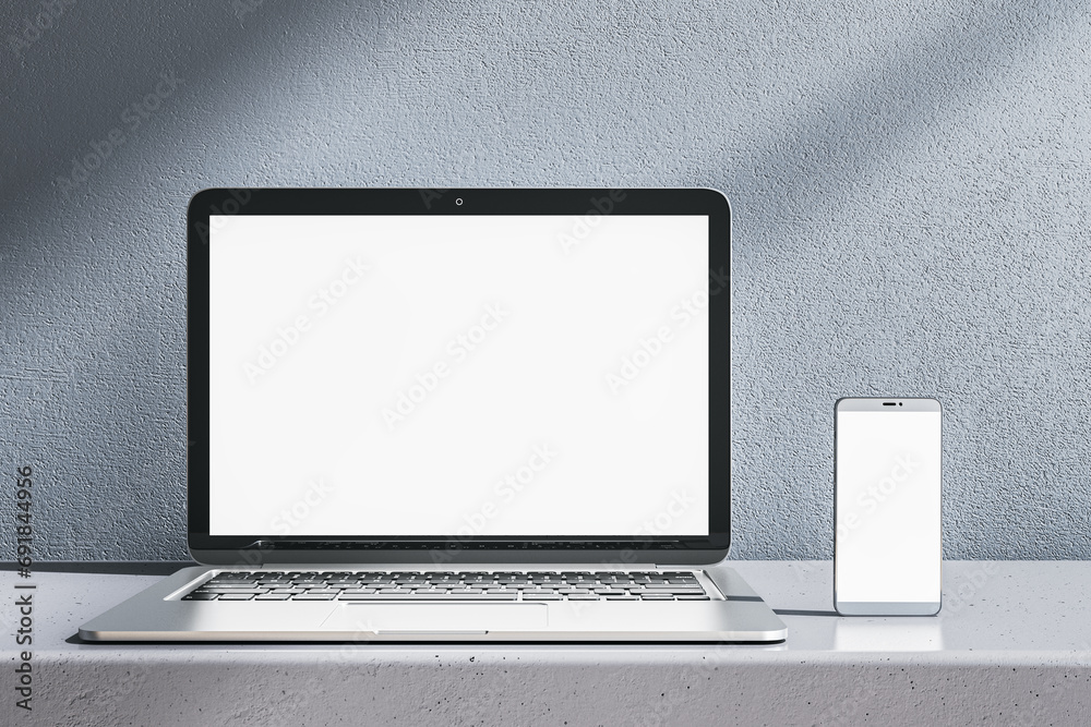 Poster close up of empty white laptop and smartphone on gray desk. concrete wall background. device present