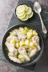 Chicken souse is a Bahamian soup that is a clear broth where the meat and the vegetables are boiled down in the juice of fresh citrus closeup on the plate on the table. Vertical top view from above