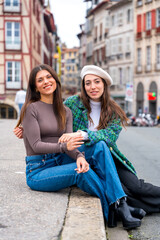 Stylish friends sitting on a beauty square in the city