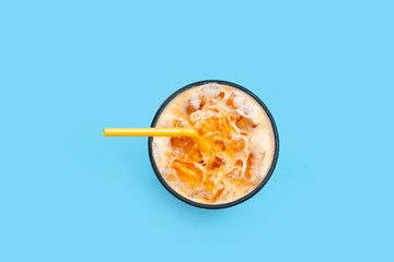 Ice Thai tea with milk on blue background.