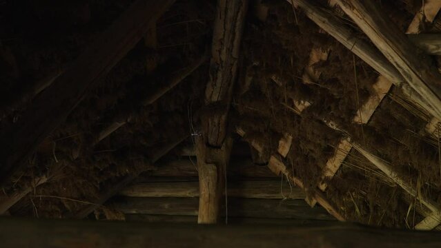 Gable wooden reed roof of old hut, inside view. Fire hazardous roof covering of country houses. Building in authentic village.