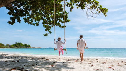 A couple of men and women at a swing on the beach of Koh Samet Island Rayong Thailand, the white...