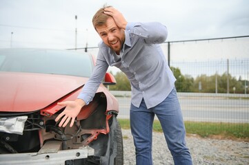 A frustrated man near a broken car. Grabbed my head realizing the damage is serious, the car is...