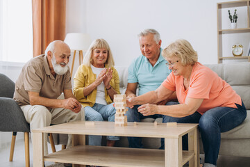 Group of happy senior people having fun and playing board games in retirement home