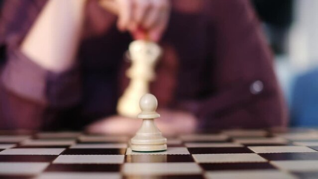 A focused chess player contemplates a move, pawn at the ready. The strategic decision echoes life's complex choices. pawn stands alone on the chessboard; a decisive moment.