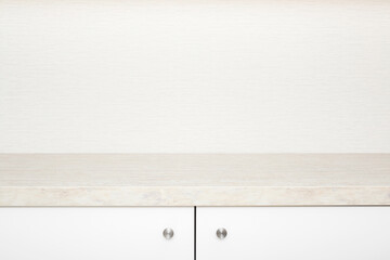 White cabinet doors with stainless handles under stone table top. New kitchen furniture. Closeup. Front view. Empty place for text on beige wallpaper background.
