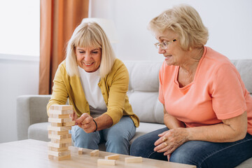 Two senior women female woman friends or family sisters play leisure board game at home