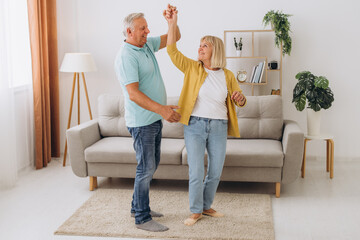 Happy senior couple dancing to music together in living room