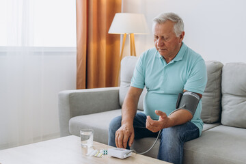 Senior man with hypertension measuring blood pressure herself at home