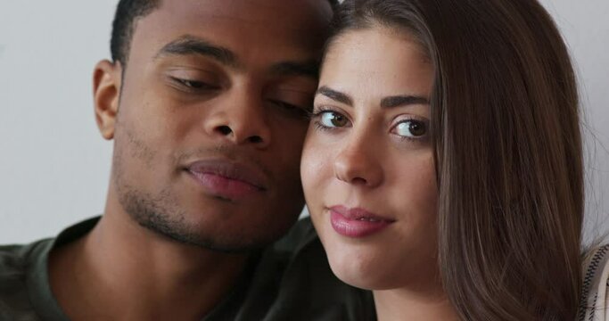 Close up portrait of black man giving his girlfriend a kiss on the cheek. White and African American millennial couple looking at camera. 4k slow motion handheld