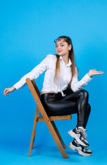 Attractive woman with glasses on forehead, smiling at camera, while sitting on chair. Side view of...