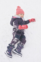 Two years old girl enjoying snow and ice in frozen city park