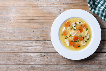 Chicken soup with vegetables on wooden table. Top view. Copy space