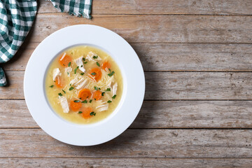 Chicken soup with vegetables on wooden table. Top view. Copy space