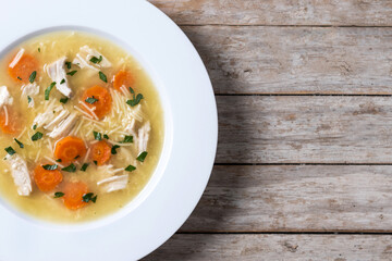 Chicken soup with vegetables on wooden table. Top view. Copy space
