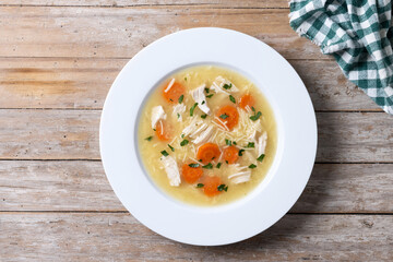 Chicken soup with vegetables on wooden table. Top view