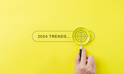 Trends 2024 year concept. Hand holding magnifying glass with 2024 trend searching bar for optimization 2024 business marketing trends and business plan in new year. Find information and new ideas. - obrazy, fototapety, plakaty