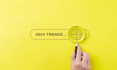 Fotobehang Trends 2024 year concept. Hand holding magnifying glass with 2024 trend searching bar for optimization 2024 business marketing trends and business plan in new year. Find information and new ideas. © Supatman