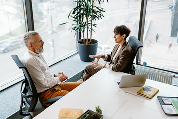 Portrait of professional man and woman sharing ideas during meeting in conference room - obrazy, fototapety, plakaty