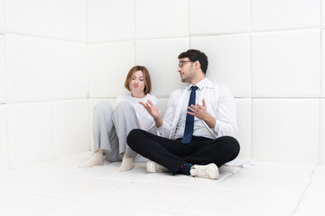 A young girl in a straitjacket sits in an isolated white room in a mental hospital and a doctor...