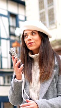 Woman with french style clothes talking to the mobile sitting in the street