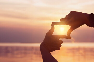 Finding inspiration and goals. A woman's hands create a frame and focus with the sunlight shining...