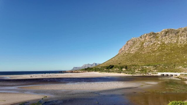View of the gorgeous Rooi Els beach and estuary with the Kogelberg Mountains and Clarence Drive in the background an a common tern (Sterna hirundo) colony on the sandbank. Western Cape. South Africa.