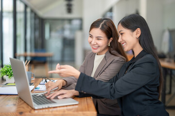 Two business colleagues talking share ideas while meeting remotely with team on laptop.