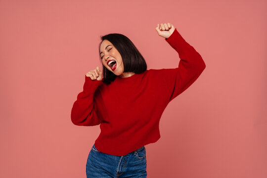 Cute Asian Woman Singing Into Imaginary Microphone Isolated Over Pink Background