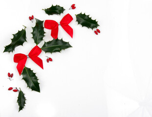 Christmas background with holy leaves, bows and red berries