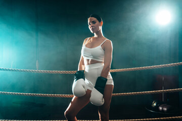 Cinematic portrait of sexy fighter woman in a boxing ring. Model wearing white gloves and braided...
