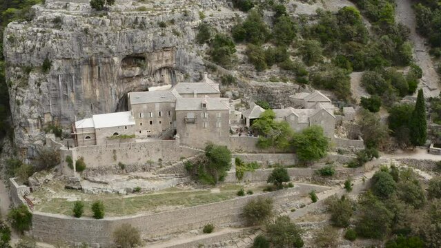 Pustinja Blaca Hermitage On Rockface Mountains In Stone Desert On Brac island, Croatia. Aerial Pullback Shot