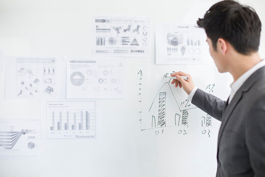 Young businessman writing on whiteboard in office