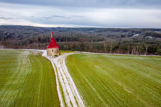 Church of the Assumption of the Virgin Mary in Dobronice near Bechyně. Snow covered path in the field. South Bohemia