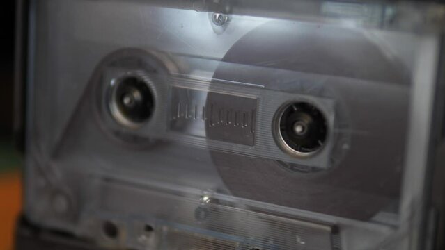 close-up analog audio cassette rotates playing music in a vintage tape recorder. retro music equipment from the 80s. audio cassette macro