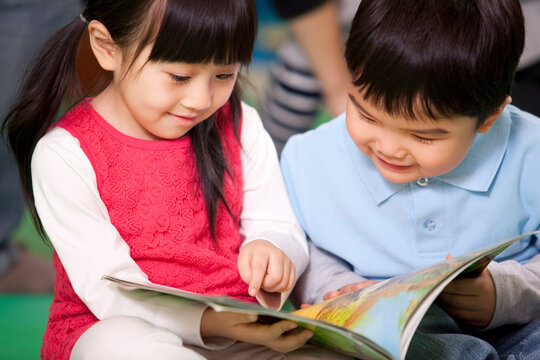 Cute little girl and little boy reading books